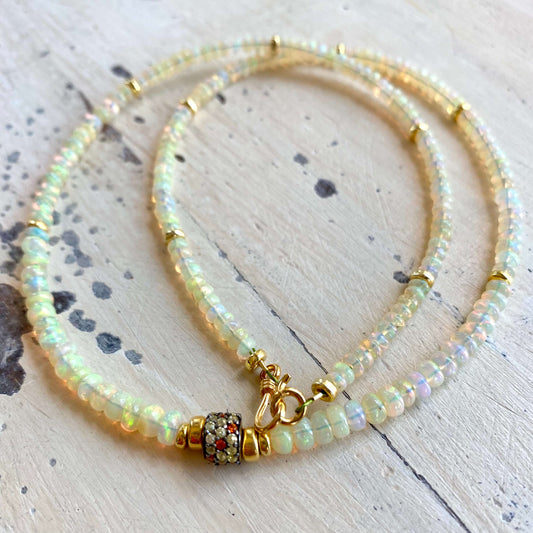 Ethiopian opal necklace flat lay, hand-knotted opal rondelles with sapphire pavé accent bead