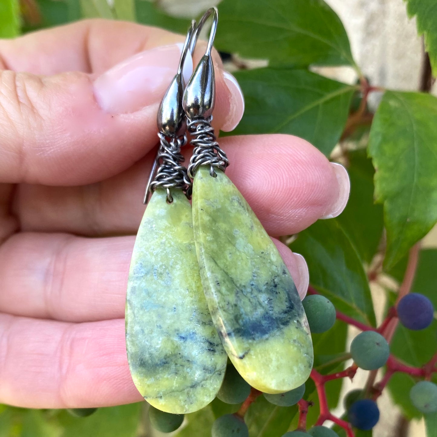 Close-up of green serpentine teardrop earrings highlighting natural stone texture