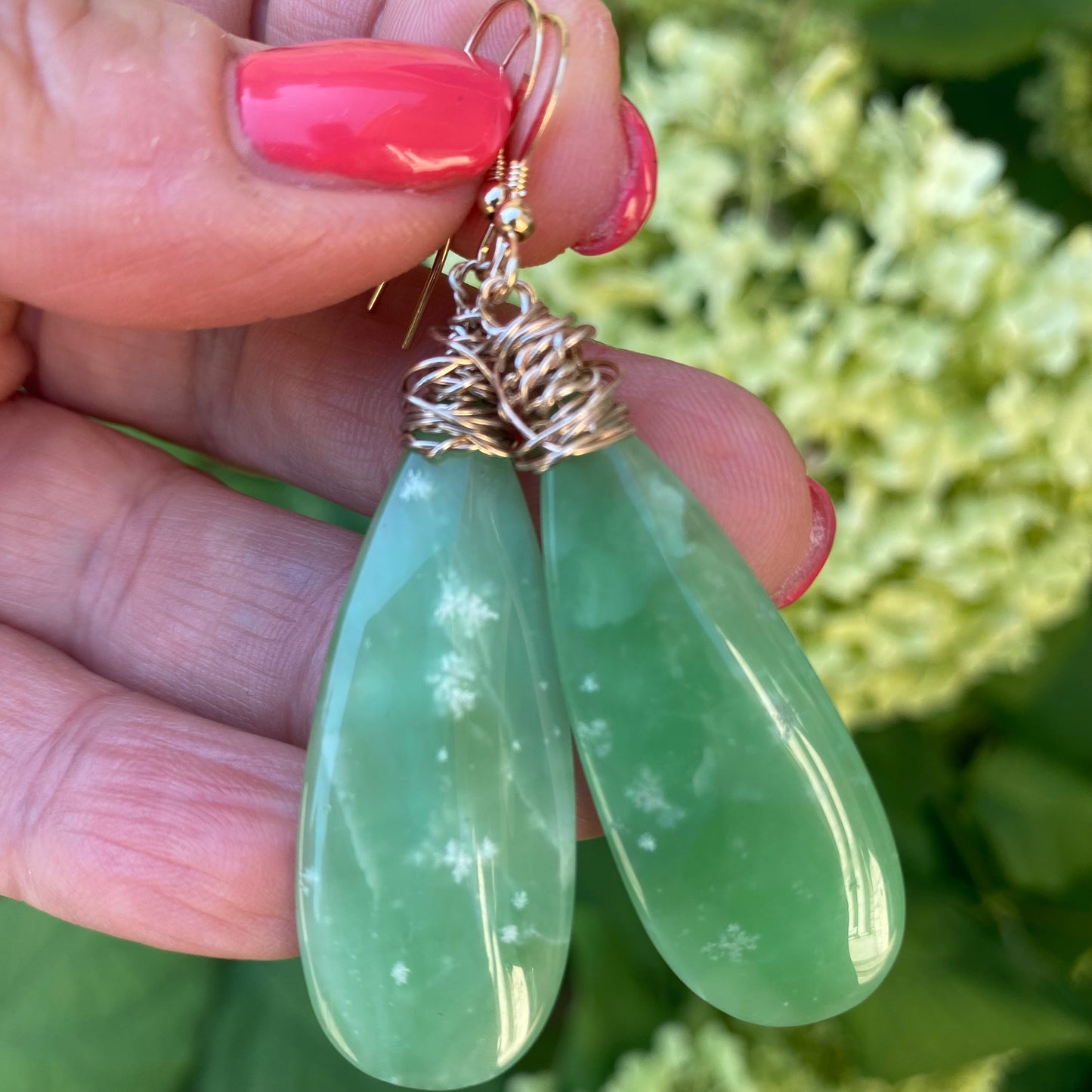 Teardrop green onyx earrings held in hand showing natural stone translucency and gold filled wire