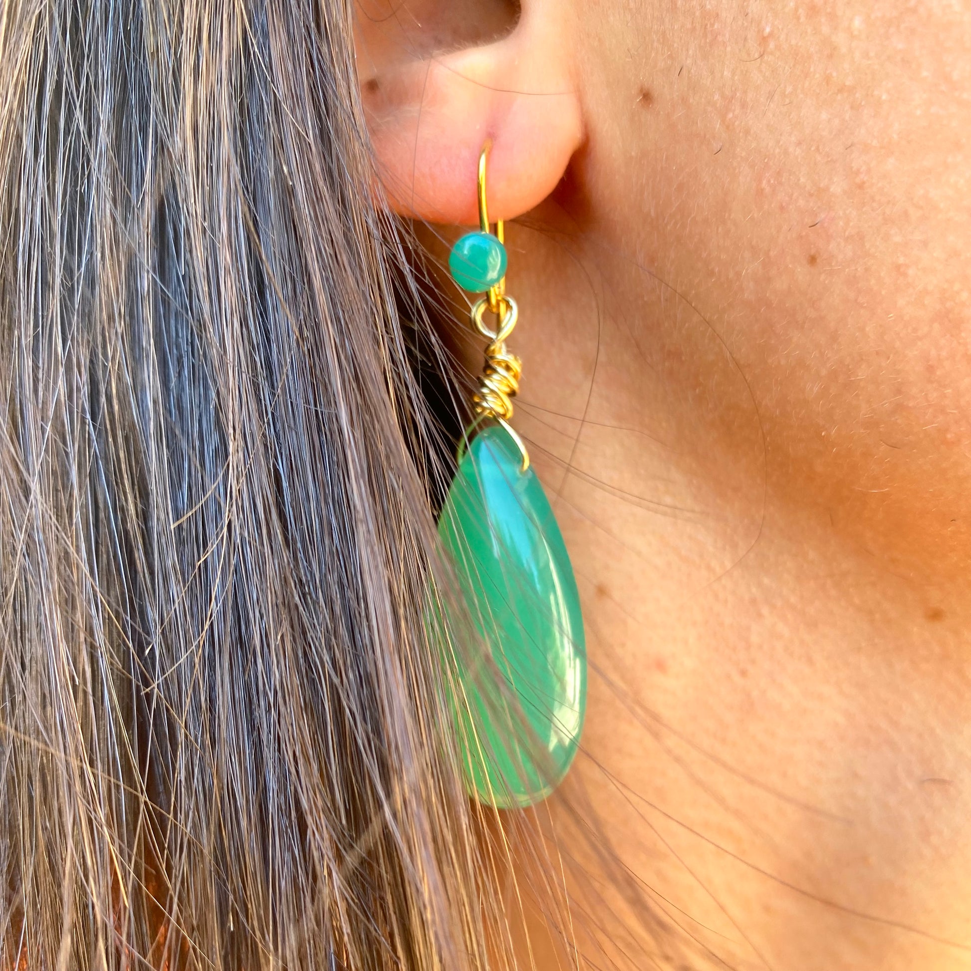 Emerald green onyx teardrop earrings worn on model highlighting elongated drop shape