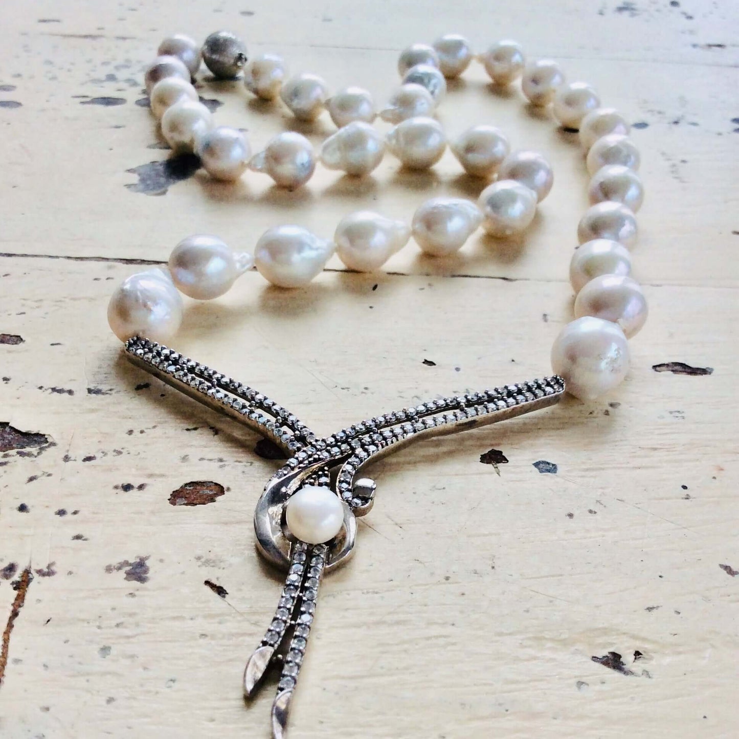 Baroque pearl necklace displayed on white wooden table, handcrafted freshwater pearls.