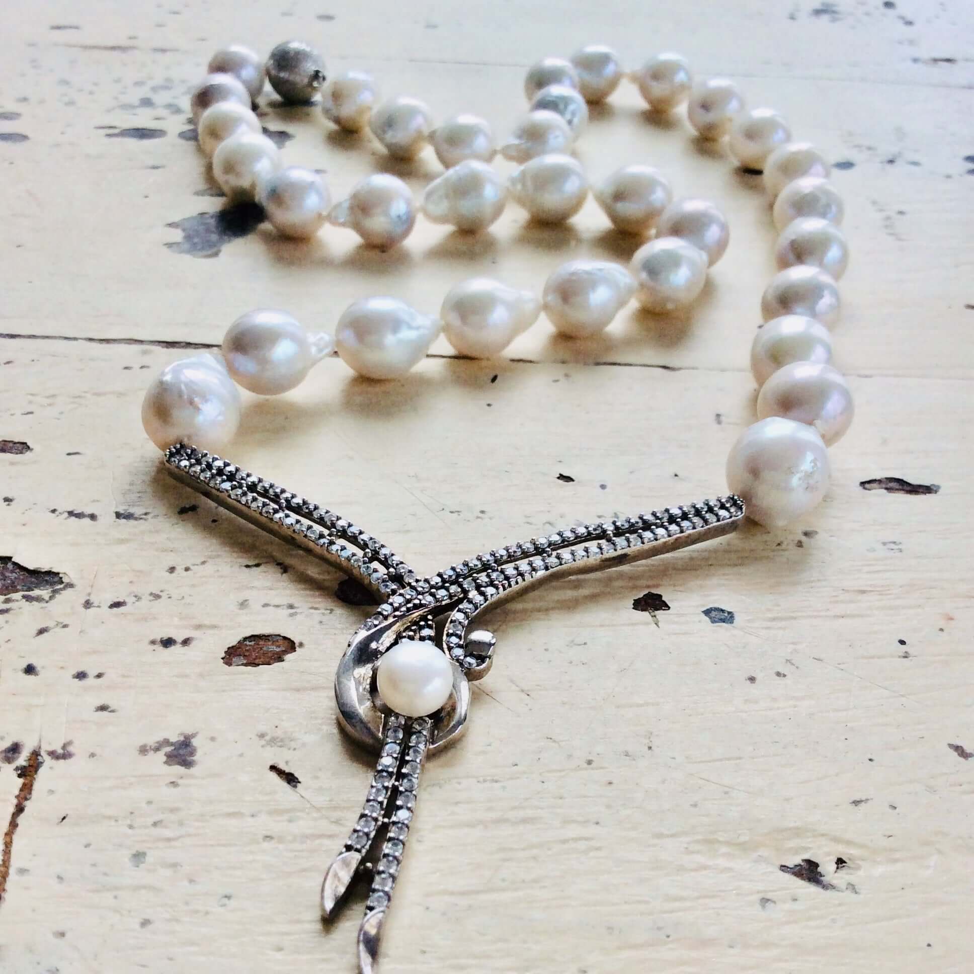 Baroque pearl necklace displayed on white wooden table, handcrafted freshwater pearls.