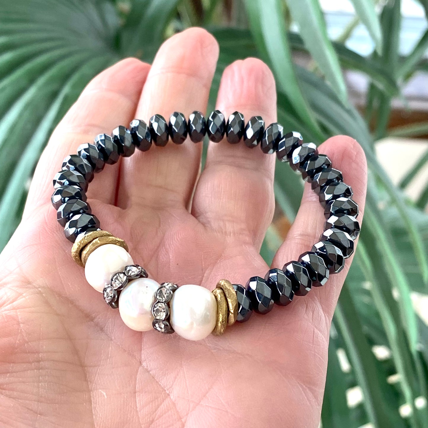 Freshwater pearl hematite stretch bracelet held in hand showing faceted hematite beads and pearls