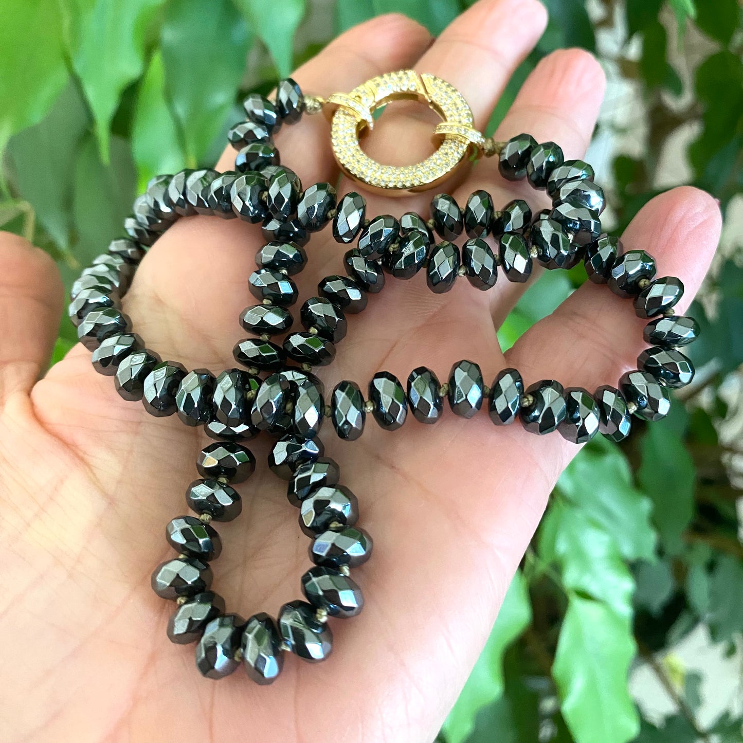 Festive Hematite Necklace showcased in hand, featuring colorful candy-shaped beads and a sparkling clasp.