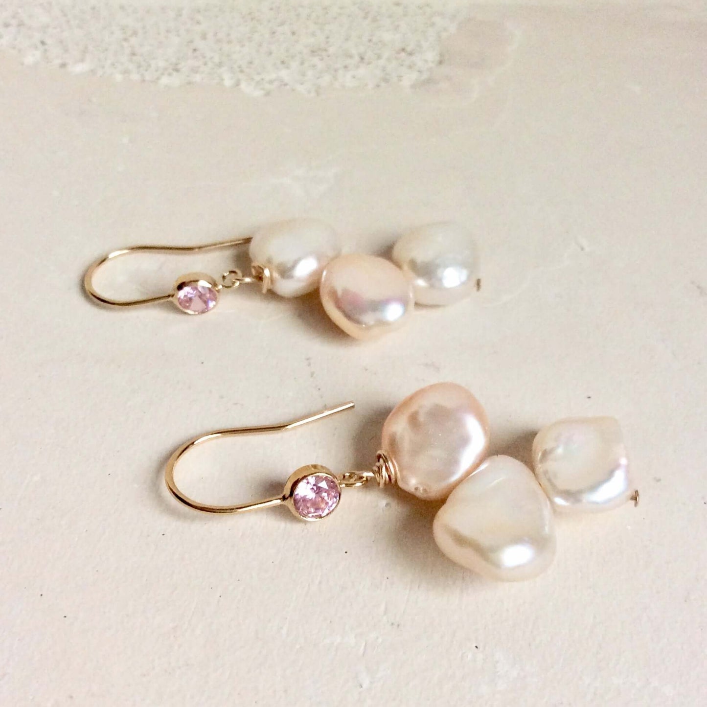Elegant earrings composed of Natural Keshi pink and white pearls hanging from gold filled hooks with pink cubic zirconia bezel
