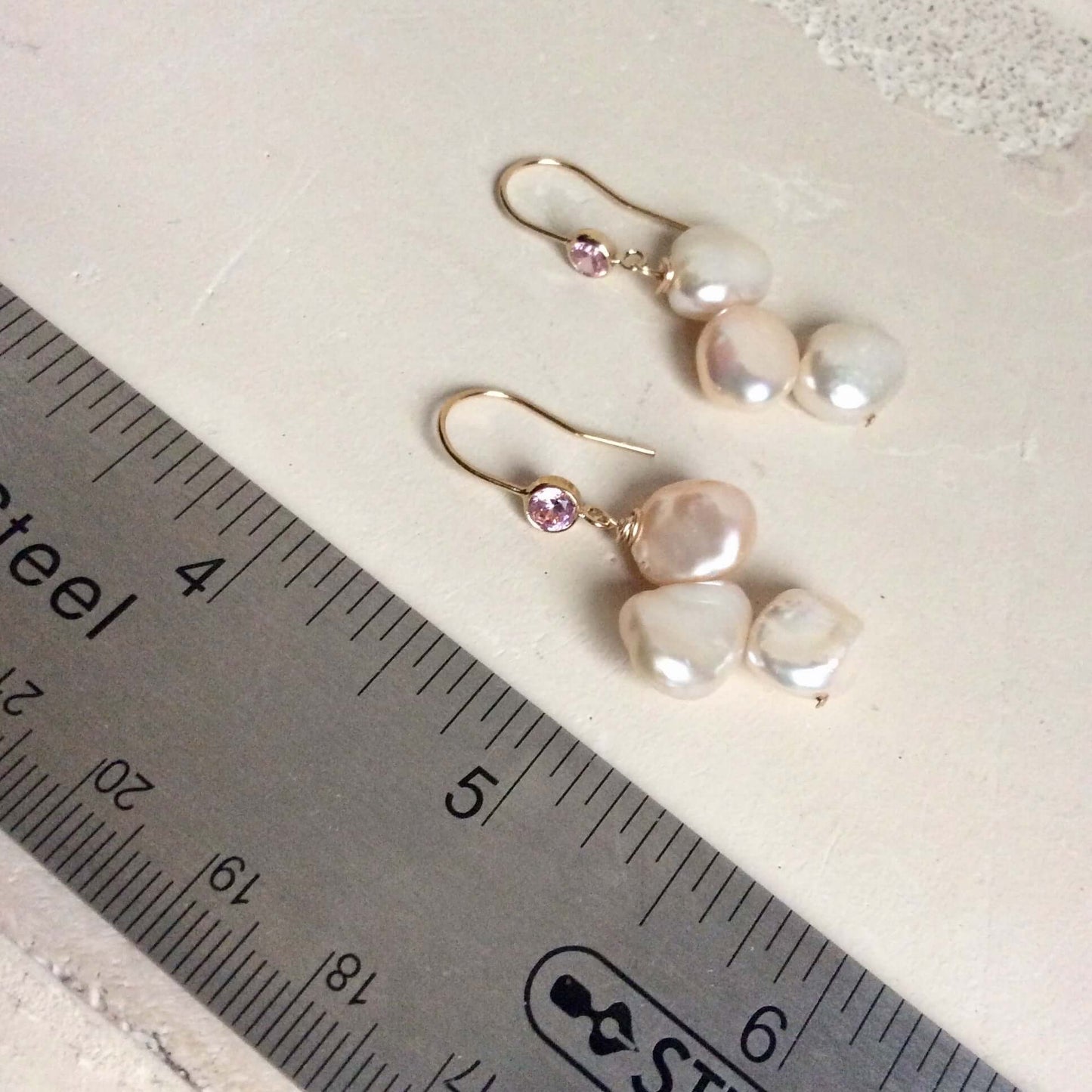 Elegant earrings composed of Natural Keshi pink and white pearls hanging from gold filled hooks with pink cubic zirconia bezel
