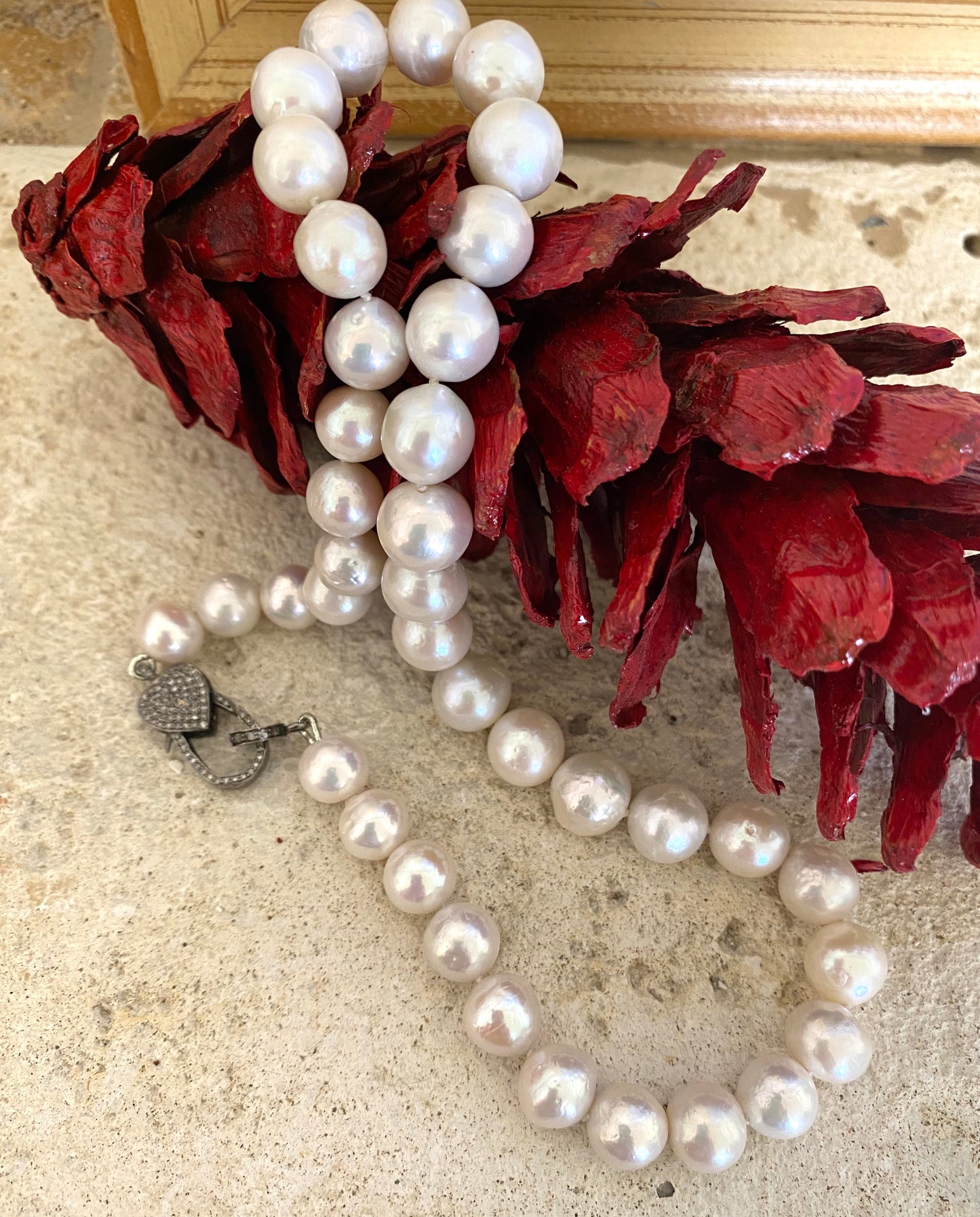 Edison pearl necklace with heart pavé diamond clasp displayed elegantly among decorative red petals.