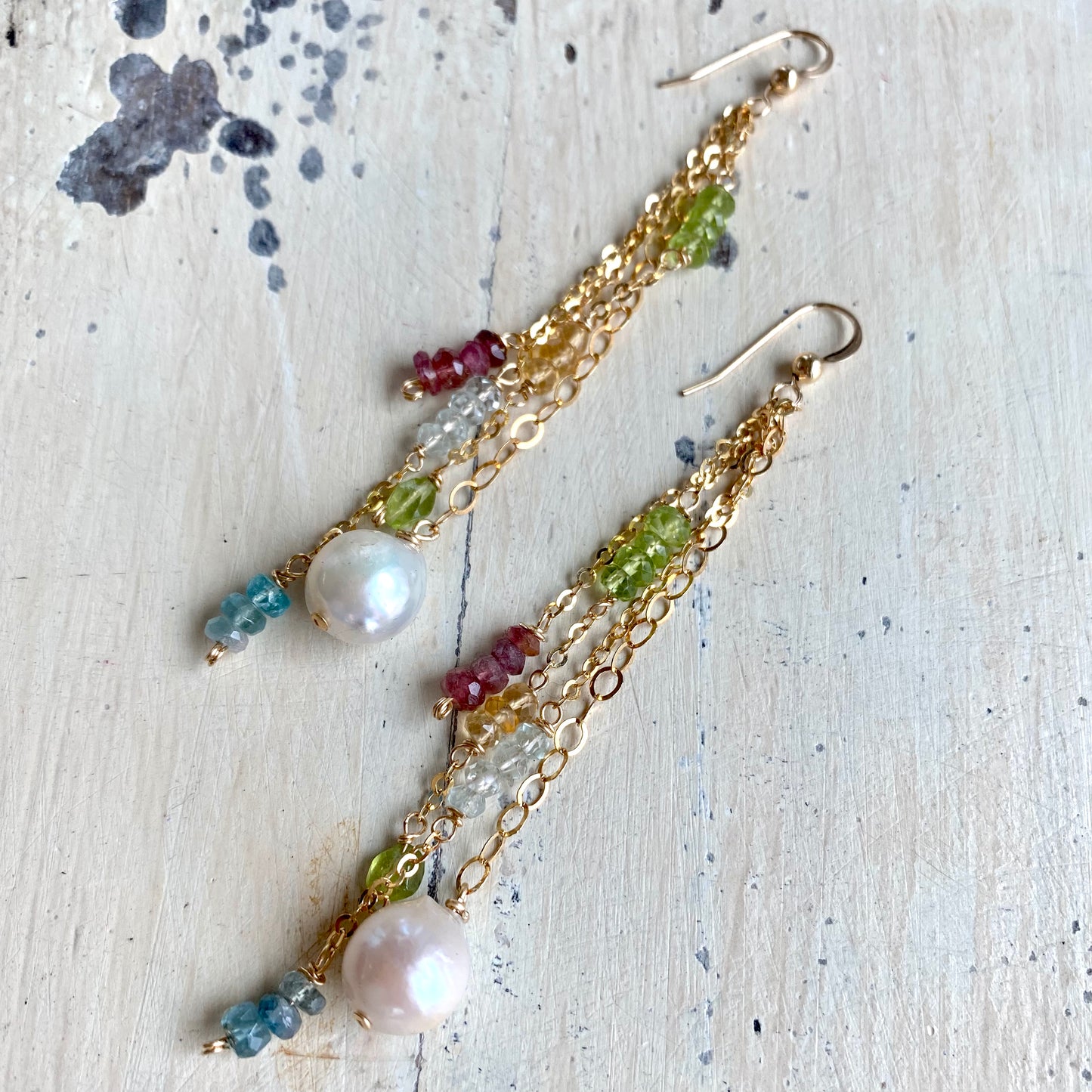 Close up of baroque pearl gemstone earrings with aquamarine peridot and citrine