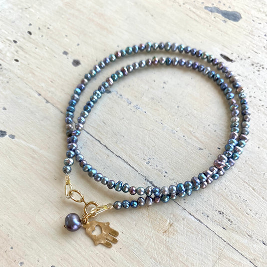 Black pearl hamsa necklace laid flat with mini rice pearls and gold filled hamsa charm, handmade Canadian jewelry