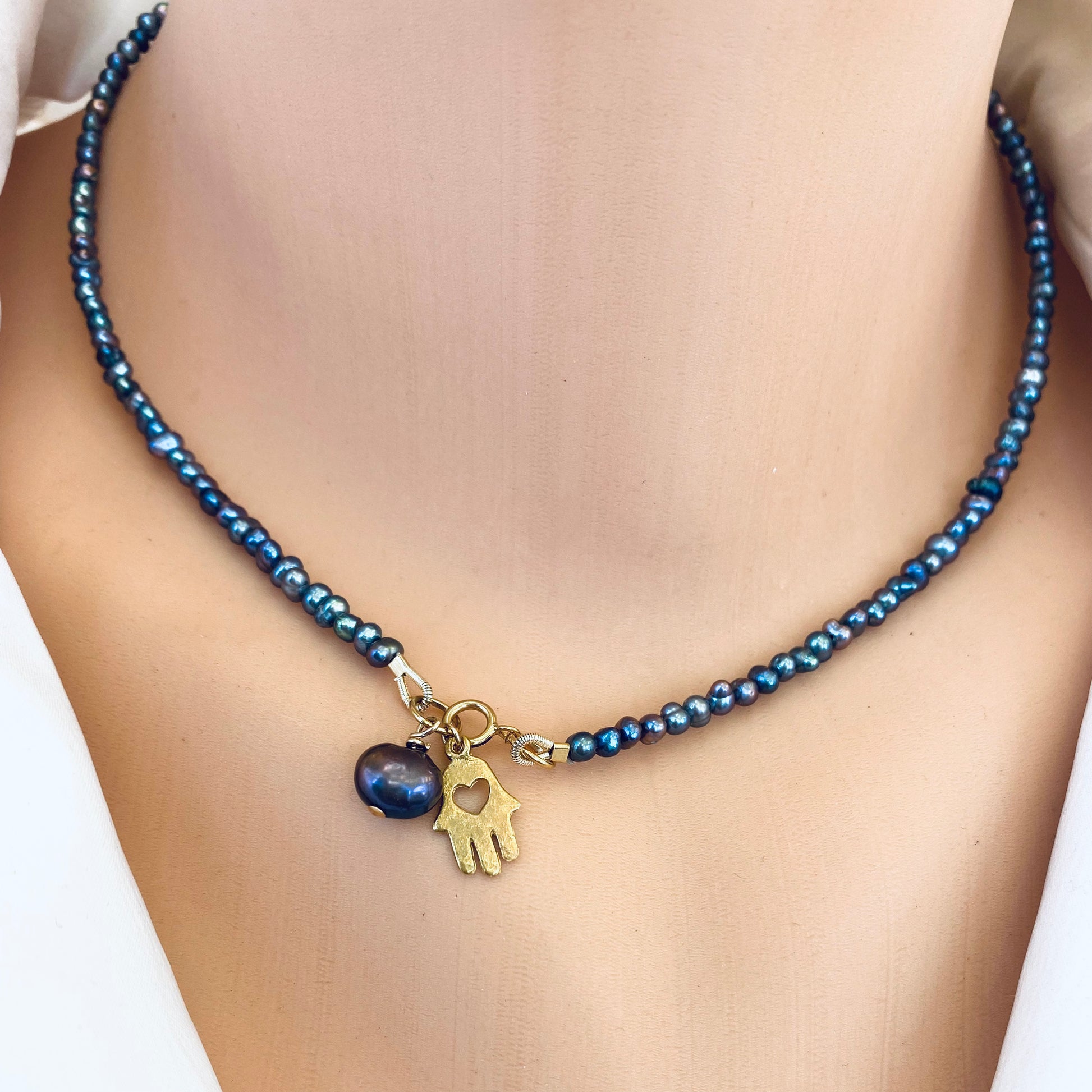 Black pearl hamsa necklace worn on neckline with 14k gold filled charm, handmade in Canada