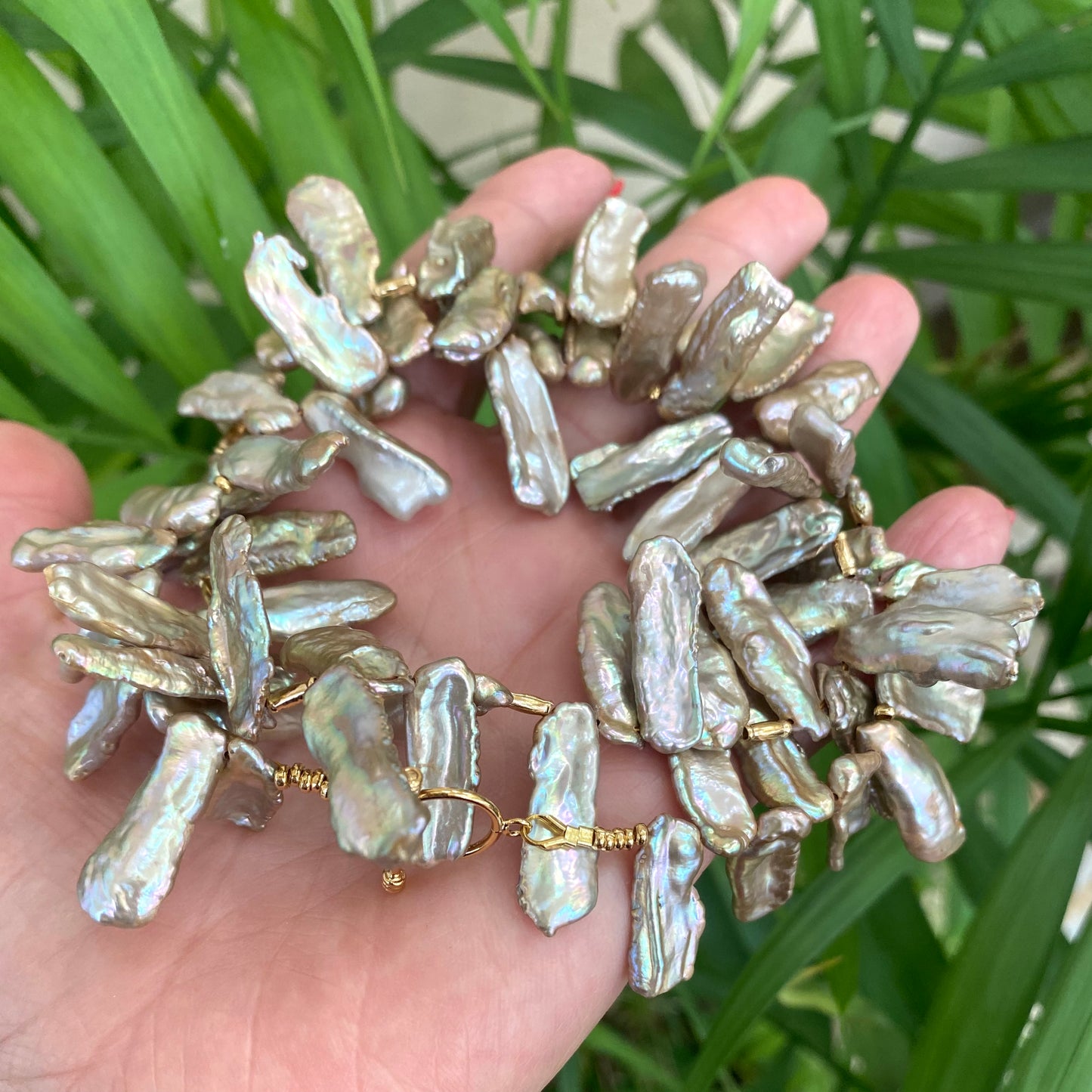 Champagne pearl necklace in hand, chunky keshi pearls showing champagne gold and pink luster