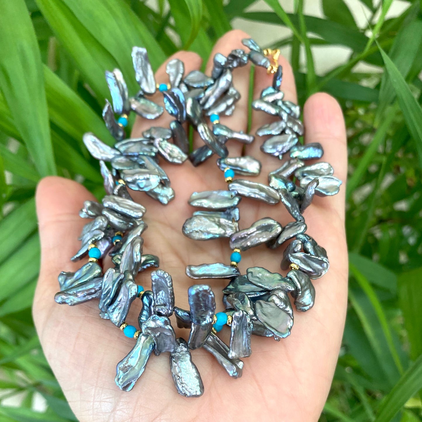 Biwa pearl turquoise necklace in hand, blue grey keshi pearls showing iridescent luster and turquoise beads