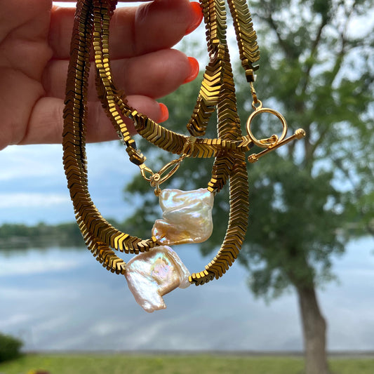 Gold hematite keshi pearl necklace held in hand highlighting gold tone and luminous keshi pearl