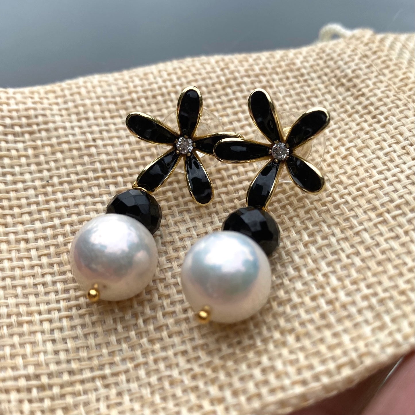 Edison pearl black spinel earrings on beige fabric, black flower studs with CZ center and white pearl drop