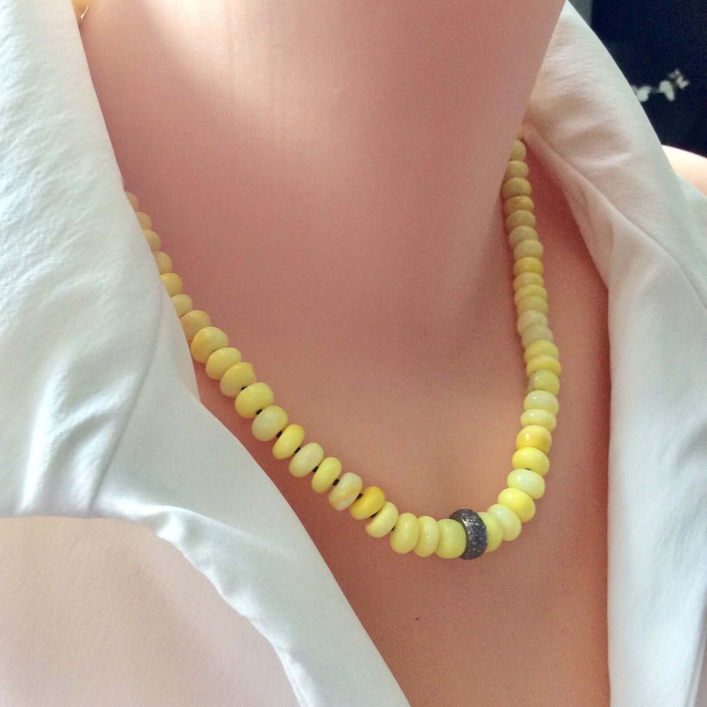 Yellow opal necklace with diamond accents elegantly displayed on a mannequin's neck, showcasing its vibrant color.