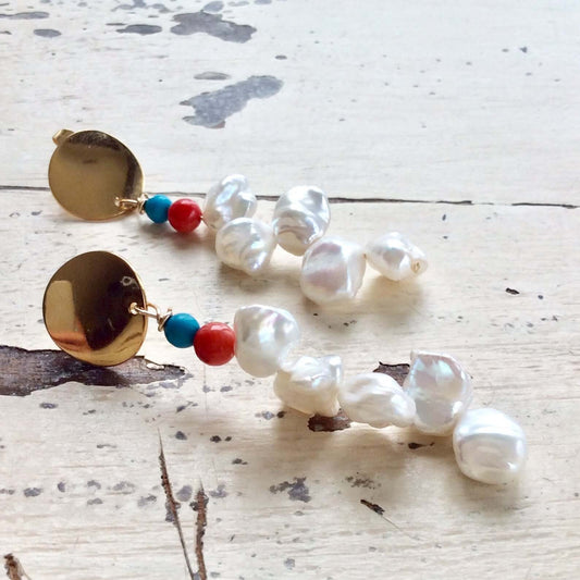 Baroque Keshi Pearl Earrings with gold dangle and turquoise, red coral accents on a rustic background.